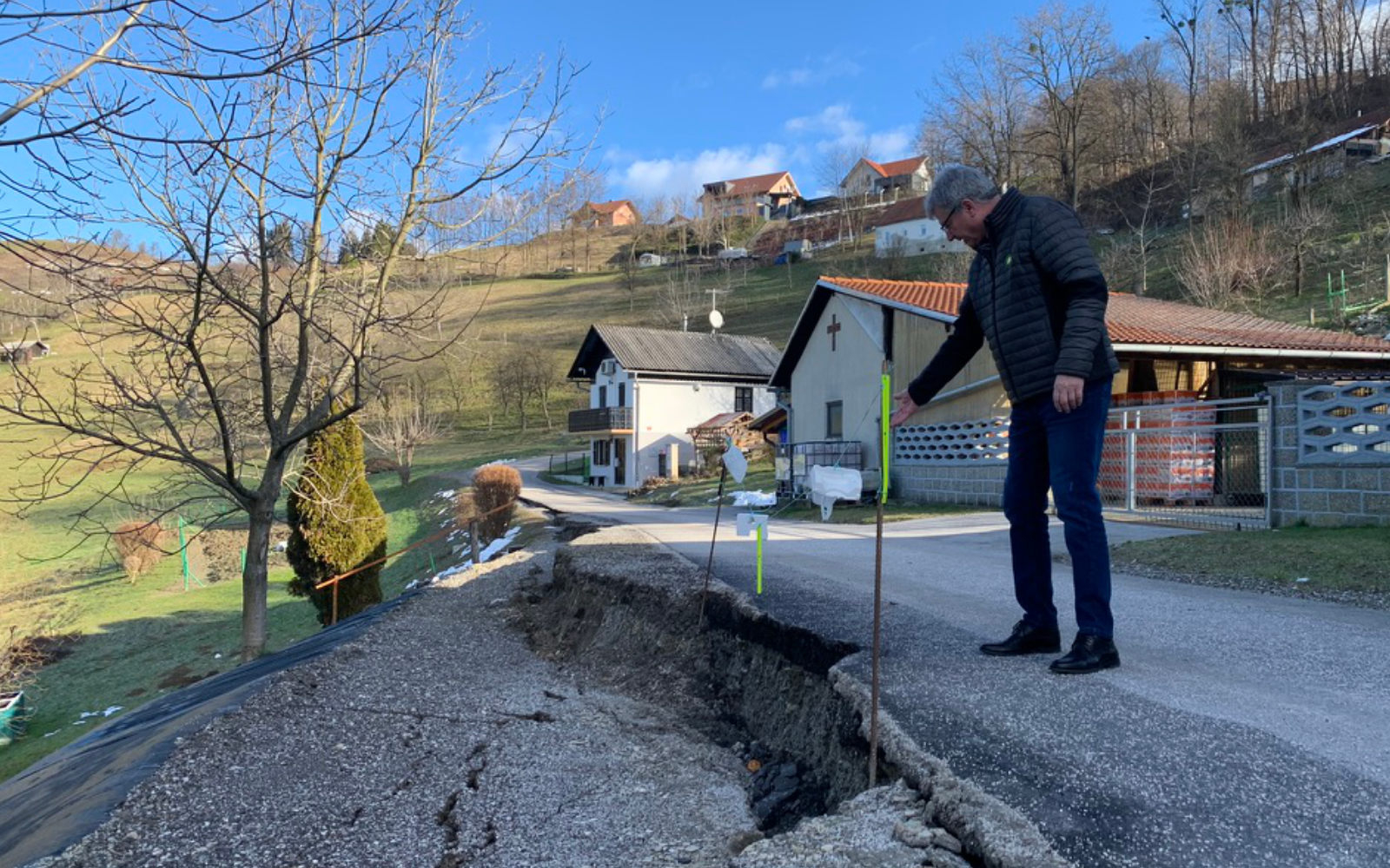 Župan Peter Škrlec ob plazu v Zg. Gasteraju pri družini Žunkovič. Cesta je bila še pred dobrima dvema letoma makedamska, zdaj ne izključujejo možnosti, da je do plazu prišlo zaradi asfalta, na površini katerega se voda zbira ter nato v večji količini na manjši površini odteka v zemljo. Človek s svojimi posegi vse pogosteje drastično posega v naravo, katera večkrat vrne dolg z obrestmi. Foto: Barbara Ribič
